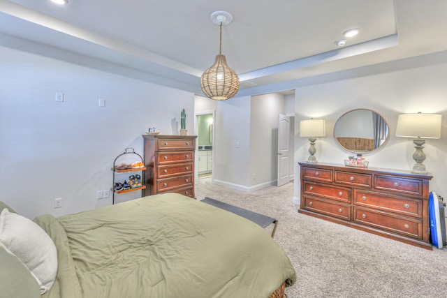 carpeted bedroom featuring connected bathroom and a raised ceiling