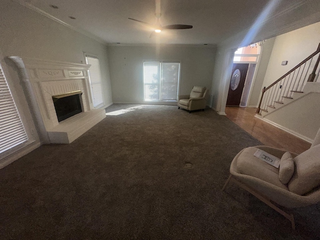 living room featuring ornamental molding, carpet flooring, ceiling fan, and a fireplace