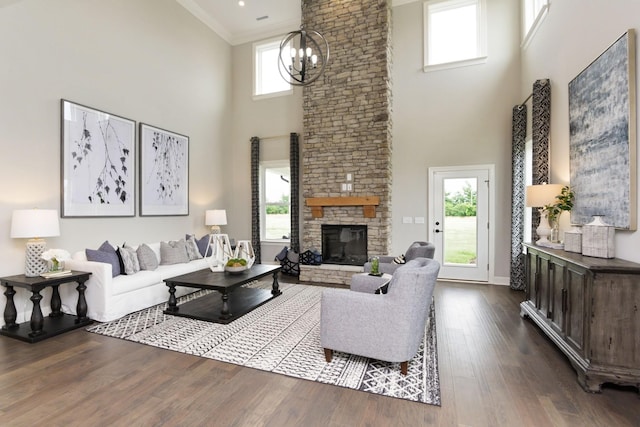 living room featuring a chandelier, ornamental molding, dark hardwood / wood-style floors, a towering ceiling, and a fireplace