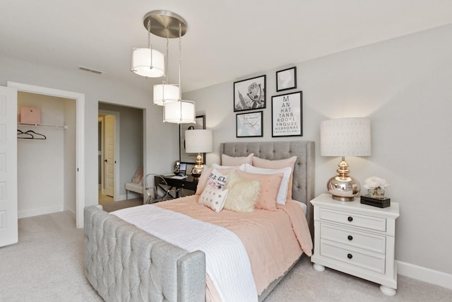 bedroom with a spacious closet, light carpet, and a closet