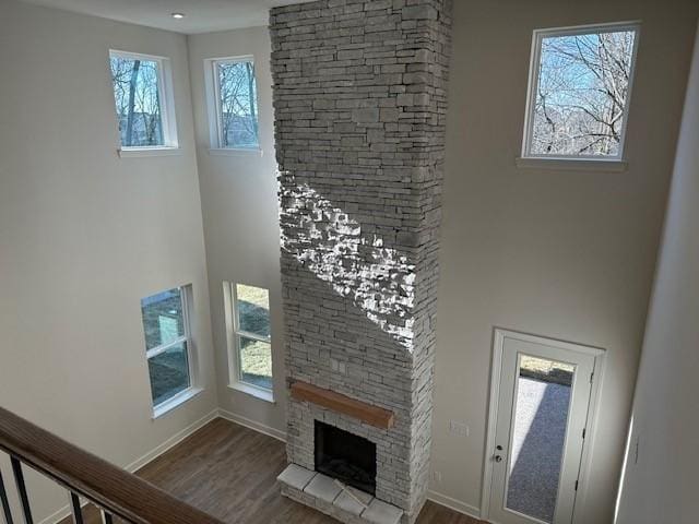 unfurnished living room featuring hardwood / wood-style flooring, a towering ceiling, and a fireplace