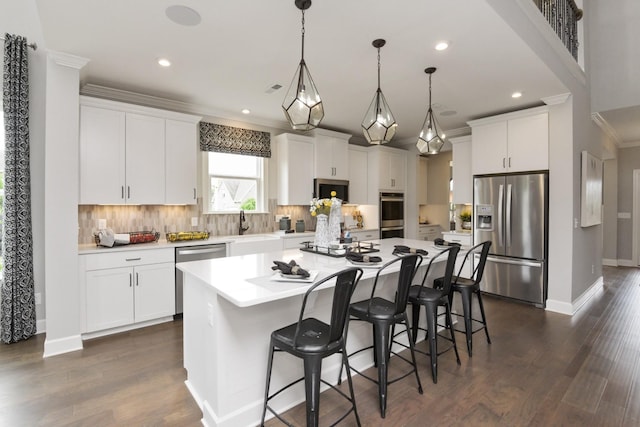 kitchen with stainless steel appliances, white cabinetry, a center island, and pendant lighting