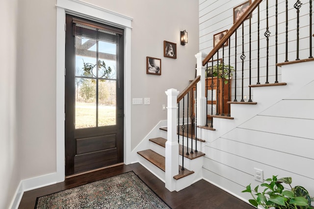 entryway with a wealth of natural light, dark hardwood / wood-style floors, and wooden walls