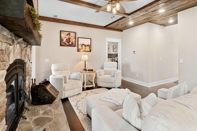 living room featuring beamed ceiling, ceiling fan, a stone fireplace, and hardwood / wood-style floors