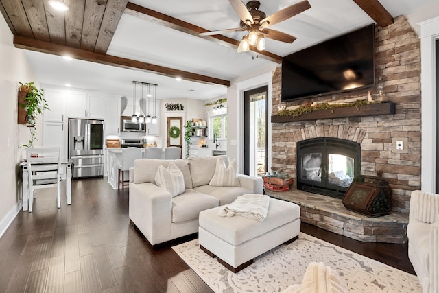 living room featuring sink, a fireplace, dark hardwood / wood-style floors, and beamed ceiling