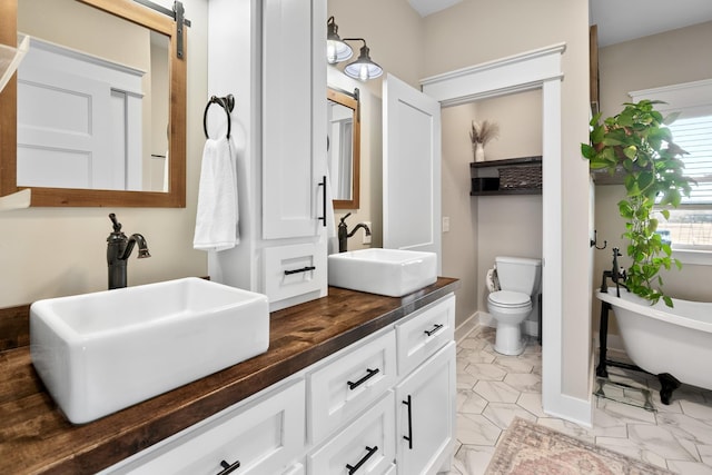 bathroom featuring vanity, a washtub, and toilet