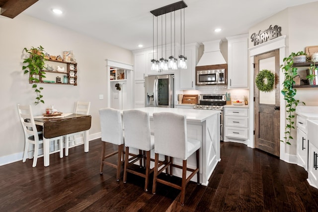 kitchen with a kitchen island, dark hardwood / wood-style floors, pendant lighting, white cabinetry, and stainless steel appliances