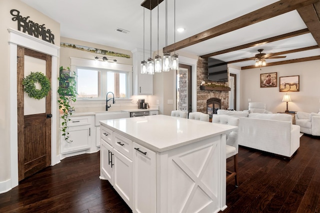 kitchen with sink, white cabinetry, hanging light fixtures, a center island, and dark hardwood / wood-style flooring