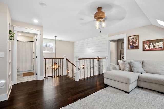 living room with hardwood / wood-style flooring, vaulted ceiling with skylight, and ceiling fan