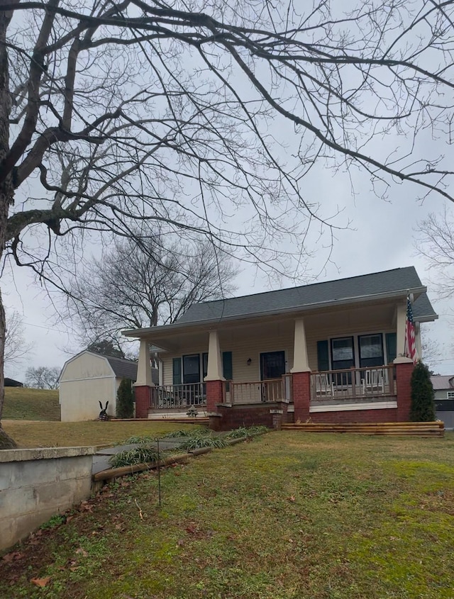 view of front of house with a storage shed, a front lawn, and covered porch