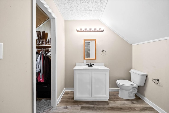 bathroom featuring vanity, hardwood / wood-style floors, lofted ceiling, and toilet