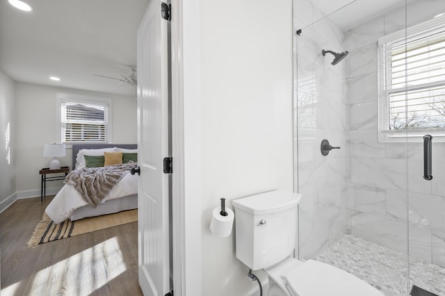 bathroom featuring hardwood / wood-style flooring, a shower with door, ceiling fan, and toilet