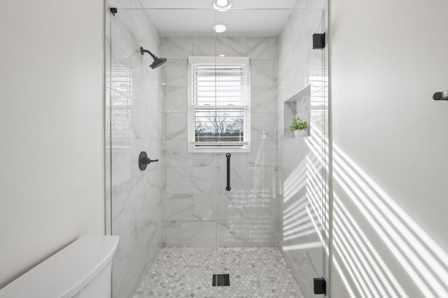 bathroom with a shower with door and toilet