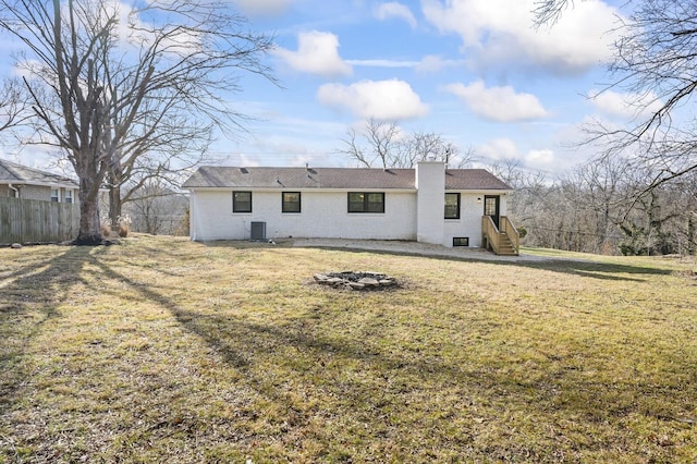 rear view of property featuring central air condition unit and a lawn