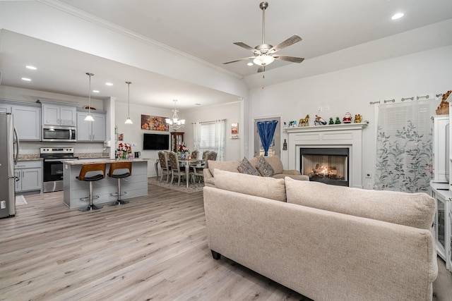 living room with crown molding, light hardwood / wood-style flooring, and ceiling fan with notable chandelier