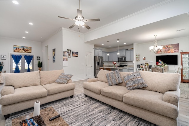 living room featuring crown molding, ceiling fan with notable chandelier, and light hardwood / wood-style floors