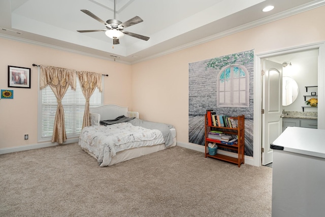 carpeted bedroom featuring ornamental molding, a raised ceiling, ceiling fan, and ensuite bathroom