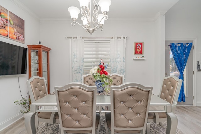 dining area with ornamental molding, an inviting chandelier, and light hardwood / wood-style flooring