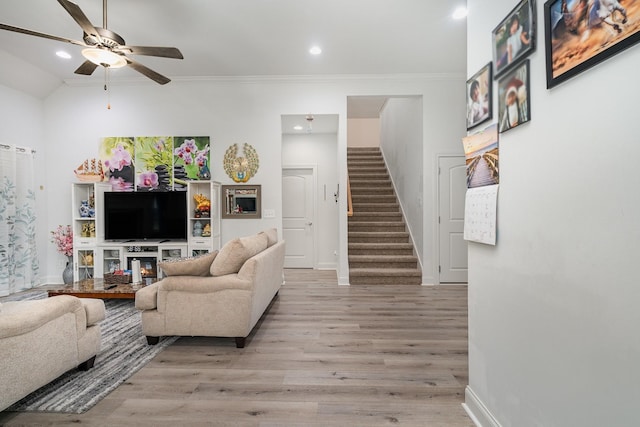 living room featuring crown molding, light hardwood / wood-style flooring, and ceiling fan