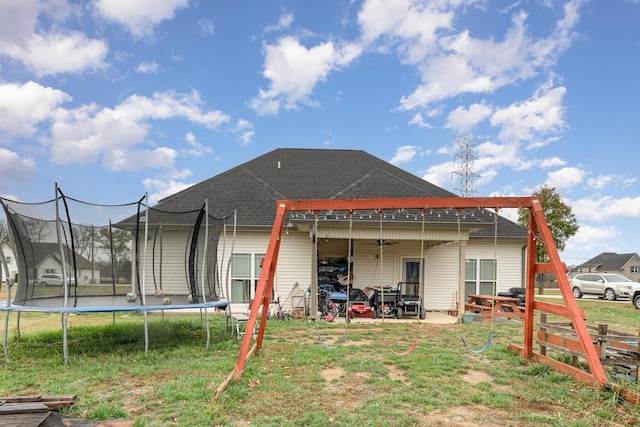 rear view of property with a patio, a trampoline, and a lawn