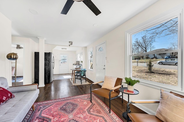 living room with dark hardwood / wood-style flooring and ceiling fan