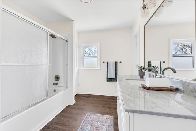 bathroom with vanity, hardwood / wood-style floors, and shower / bath combination with glass door