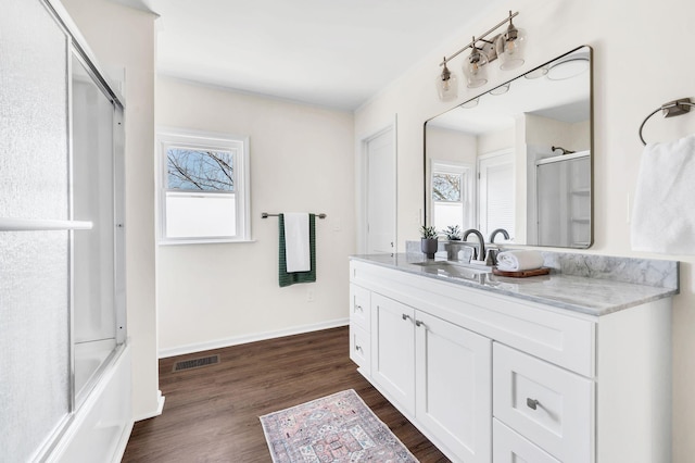 bathroom featuring vanity, hardwood / wood-style flooring, and bath / shower combo with glass door