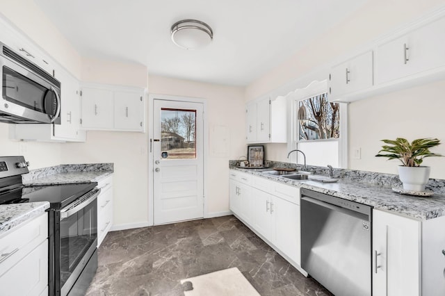 kitchen featuring stainless steel appliances, sink, white cabinets, and light stone counters