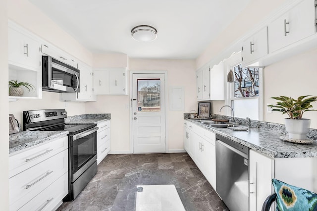 kitchen featuring light stone countertops, white cabinetry, appliances with stainless steel finishes, and sink