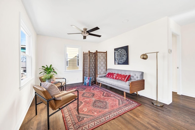 sitting room featuring dark wood-type flooring, ceiling fan, and plenty of natural light