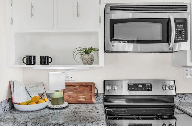 kitchen with appliances with stainless steel finishes, light stone countertops, and white cabinets