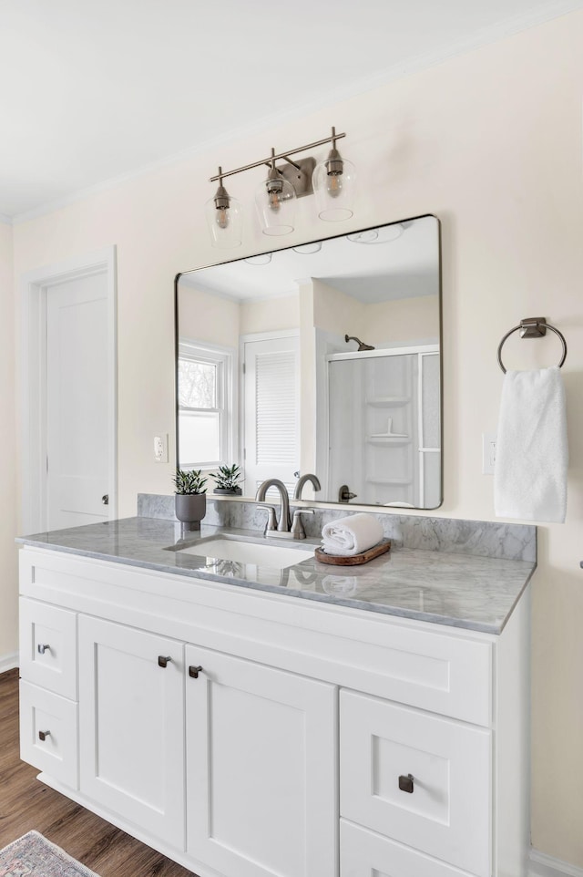 bathroom with walk in shower, ornamental molding, vanity, and wood-type flooring