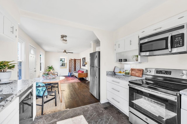 kitchen with ceiling fan, appliances with stainless steel finishes, light stone counters, white cabinets, and ornate columns