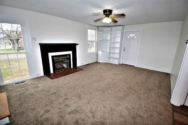 unfurnished living room with ceiling fan and dark colored carpet