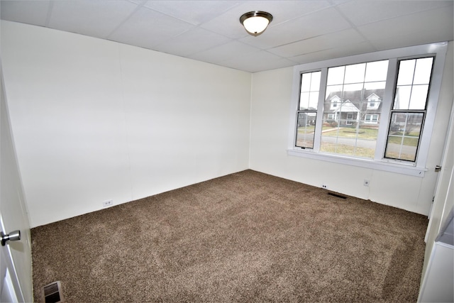 carpeted empty room with a paneled ceiling