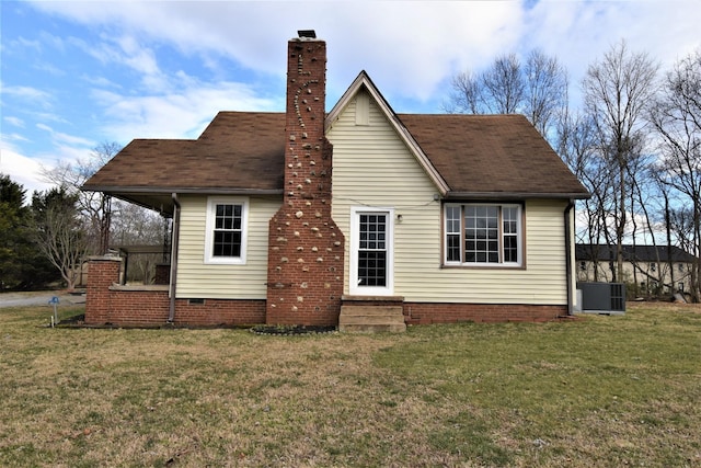 rear view of house with central air condition unit and a lawn