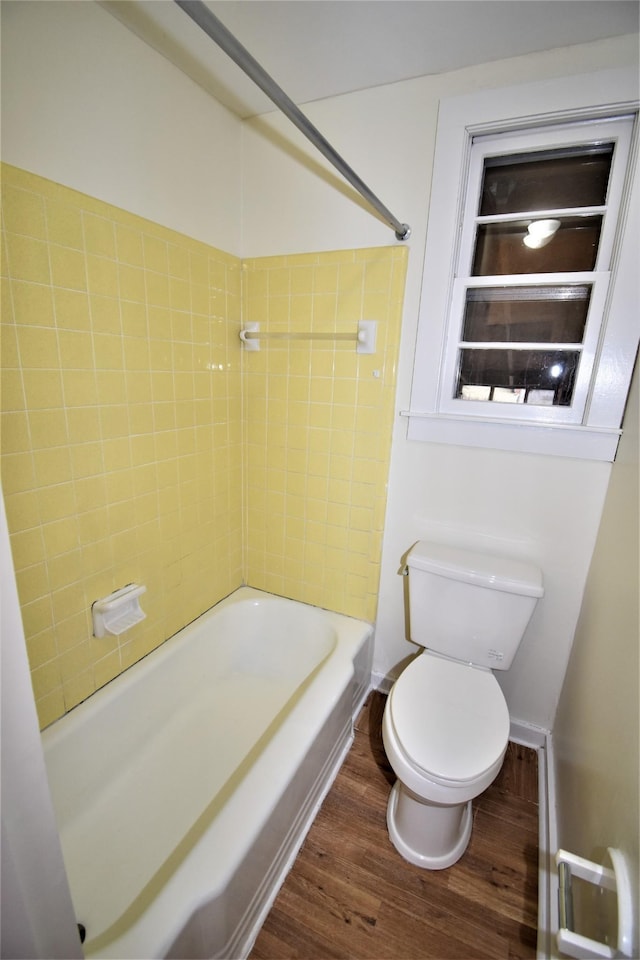 bathroom with tiled shower / bath, hardwood / wood-style floors, and toilet