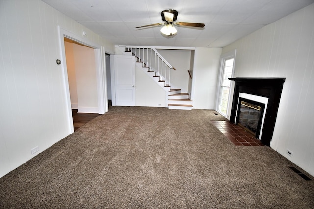 unfurnished living room featuring ceiling fan and dark colored carpet