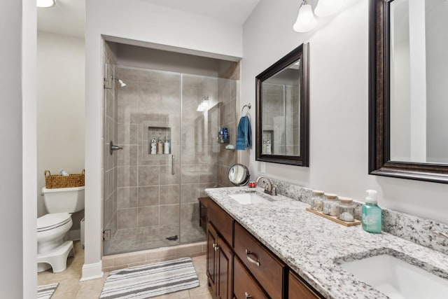 bathroom with a shower with door, vanity, tile patterned floors, and toilet