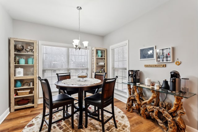 dining area with hardwood / wood-style floors and an inviting chandelier