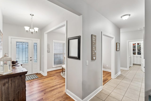 entrance foyer with a notable chandelier, a wealth of natural light, and light tile patterned flooring