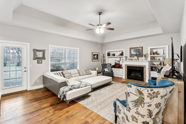 living room featuring hardwood / wood-style flooring, a fireplace, and a raised ceiling