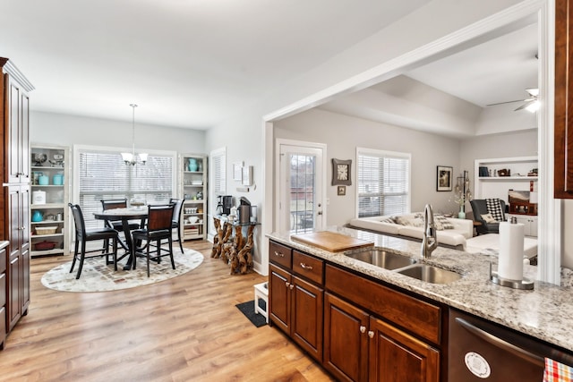 kitchen with sink, dishwasher, hanging light fixtures, light stone countertops, and light wood-type flooring