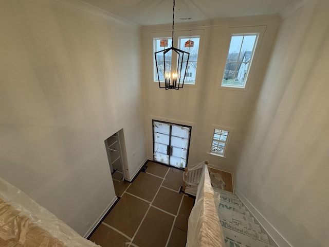 foyer with a high ceiling, crown molding, a healthy amount of sunlight, and a notable chandelier