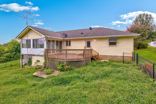 rear view of house with a sunroom, a deck, and a lawn