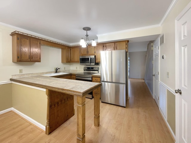 kitchen featuring decorative light fixtures, ornamental molding, tile counters, a kitchen breakfast bar, and stainless steel appliances