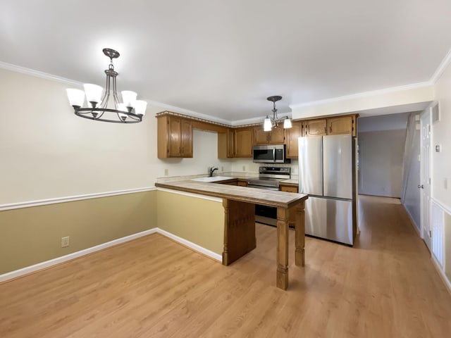 kitchen with crown molding, appliances with stainless steel finishes, kitchen peninsula, a notable chandelier, and pendant lighting