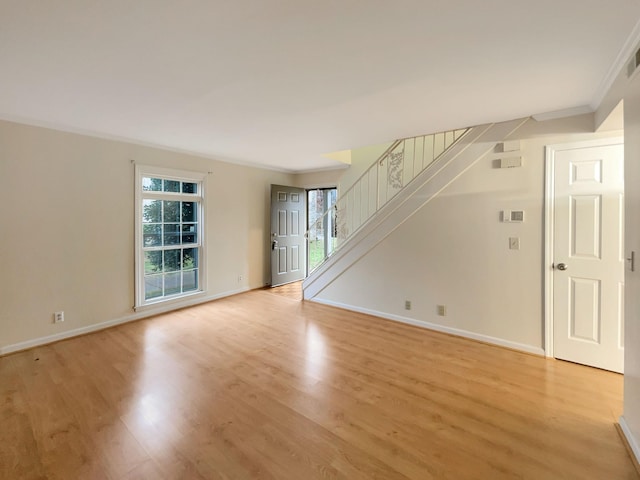 unfurnished living room featuring crown molding, a wealth of natural light, and light hardwood / wood-style flooring