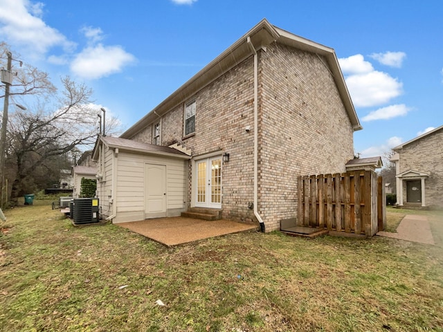 rear view of house with central AC, a patio area, french doors, and a lawn