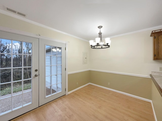 unfurnished dining area featuring ornamental molding, a notable chandelier, light wood-type flooring, and french doors